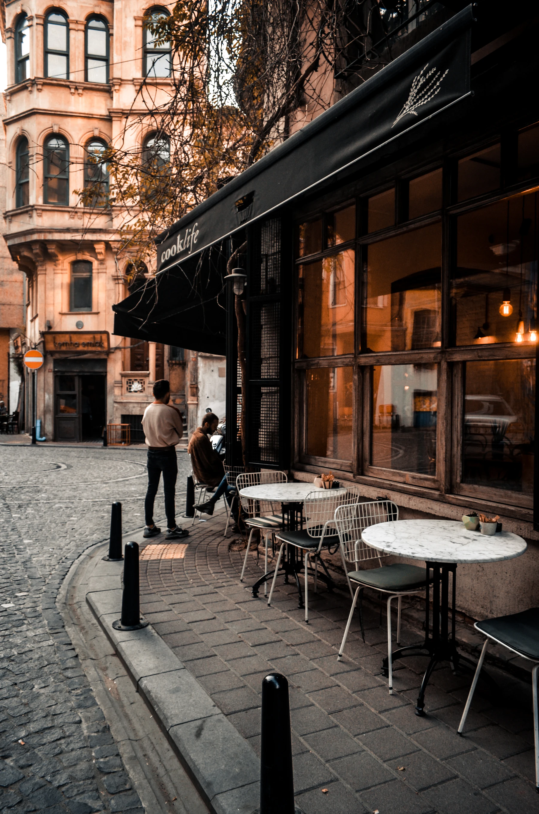 Pavement tables outside a corner café on a city street.