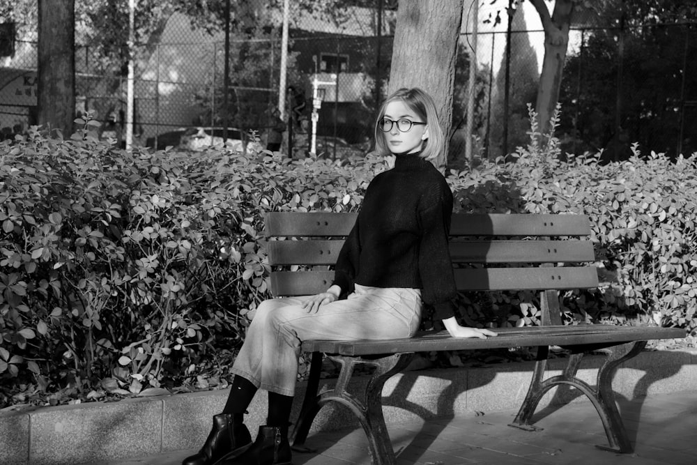 grayscale photo of woman sitting on bench