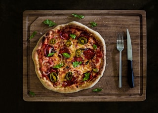 pizza with cheese and green leaves on brown wooden table