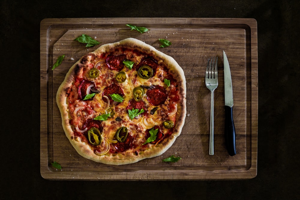 pizza with cheese and green leaves on brown wooden table