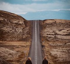 person in black jacket and brown pants walking on road during daytime