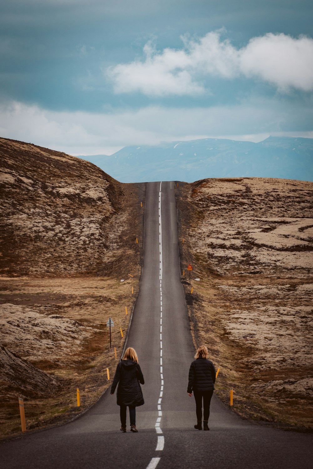 person in black jacket and brown pants walking on road during daytime