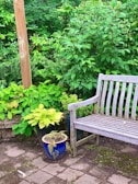 A weather-resistant patio storage bench nestled on a sunny deck with garden tools neatly stored inside.