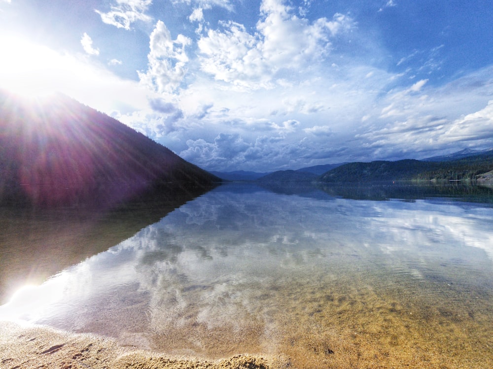 brown sand near body of water under blue sky during daytime