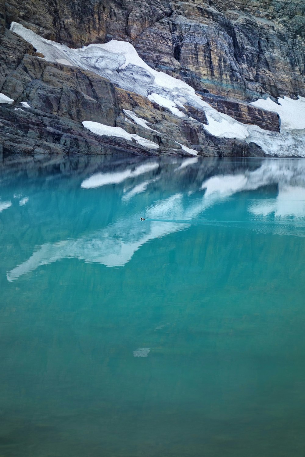 Blaues Wasser in der Nähe von weißem und grauem Rocky Mountain während des Tages