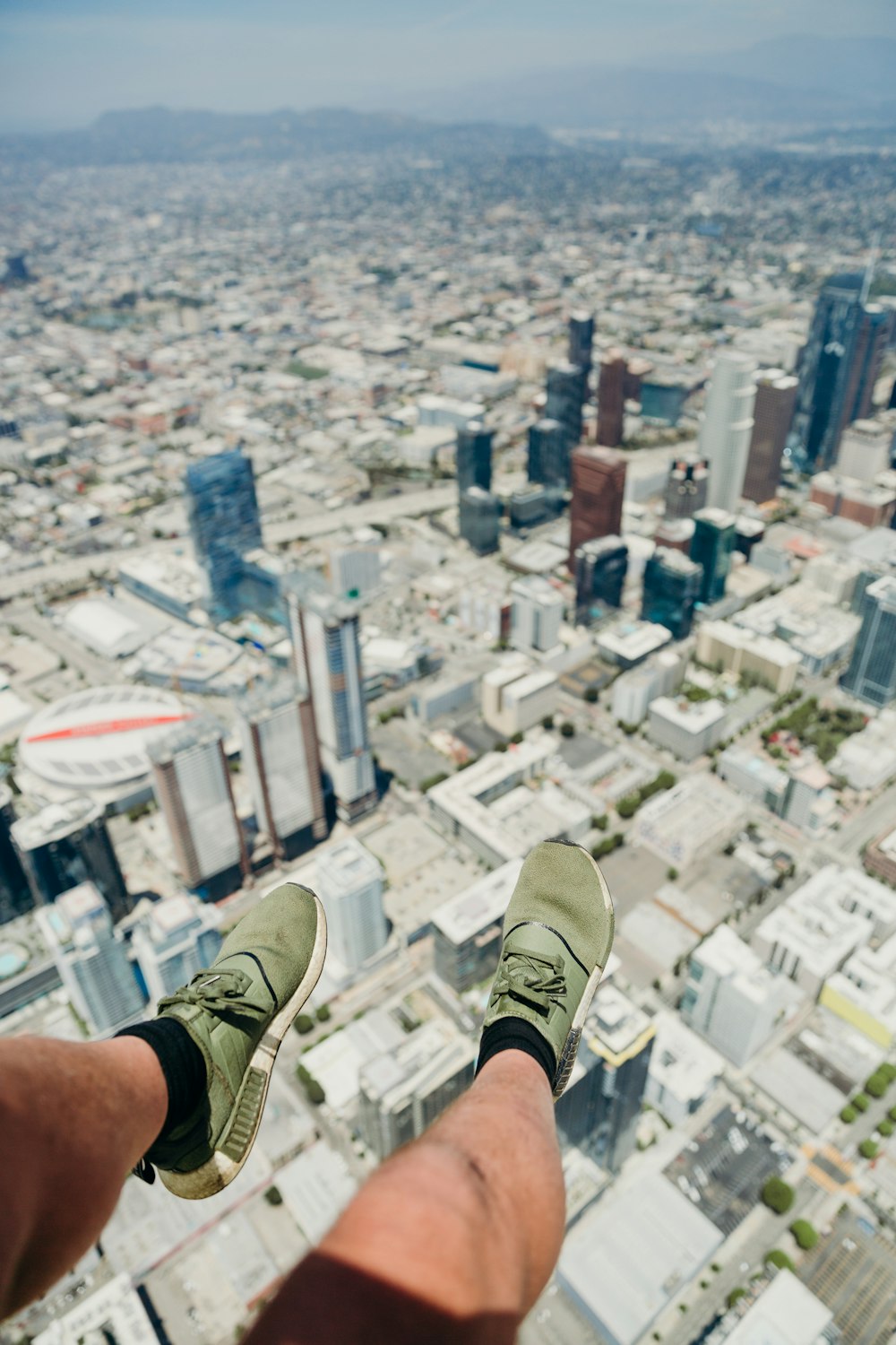person in brown and white sneakers sitting on top of building during daytime