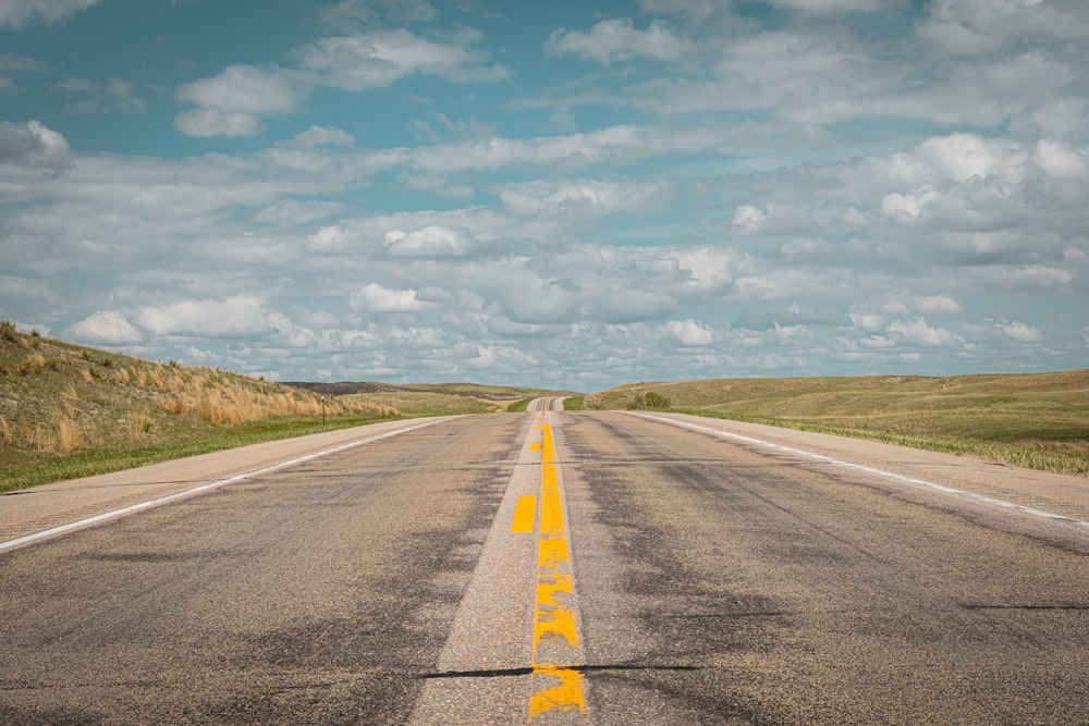 gray concrete road under white clouds and blue sky during daytime