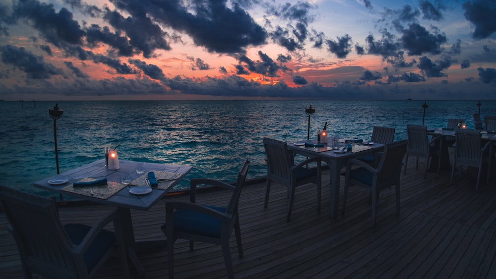 black wooden table and chairs on sea dock during sunset