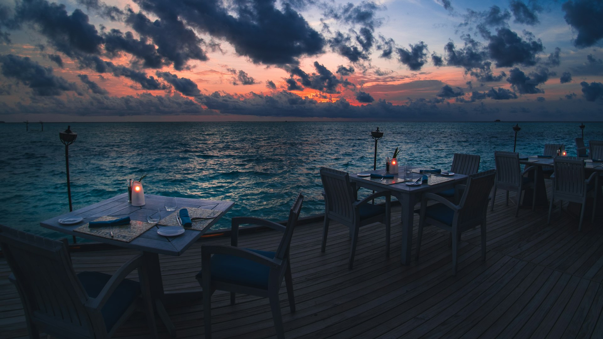 black wooden table and chairs on sea dock during sunset