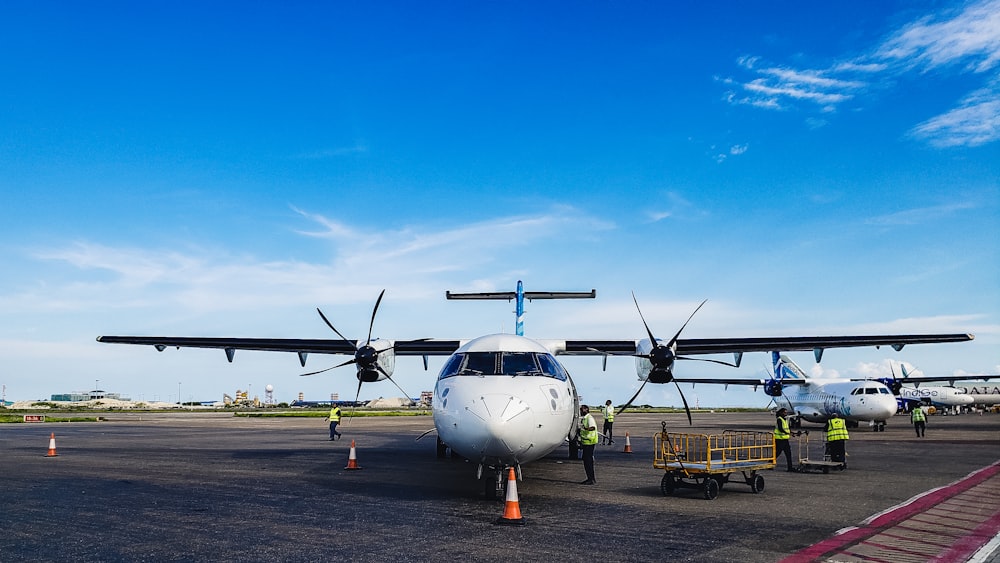 Weiß-schwarzes Flugzeug tagsüber auf grauem Betongrund unter blauem Himmel