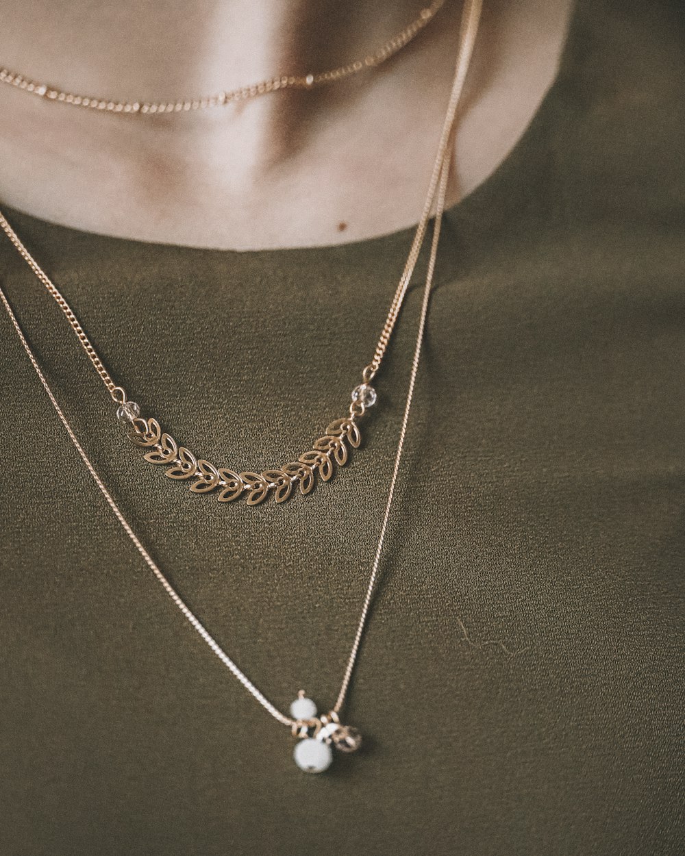 person wearing silver necklace with silver pendant