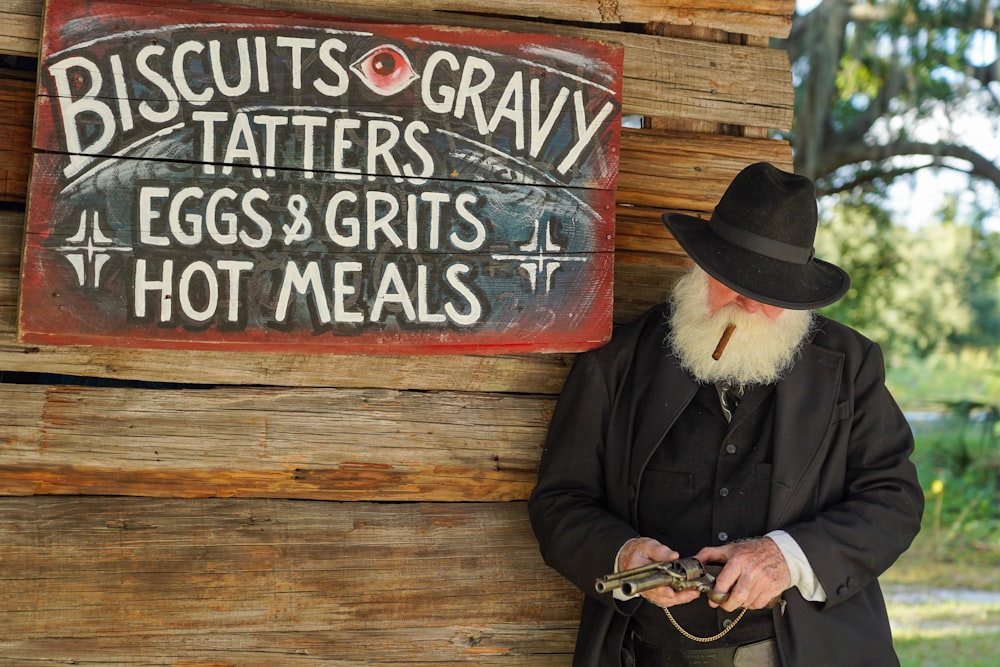 man in black coat wearing brown cowboy hat holding black and brown leather bag