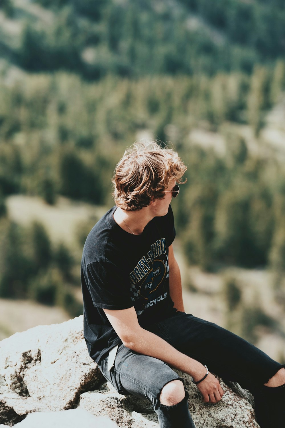 man in black crew neck t-shirt sitting on rock during daytime