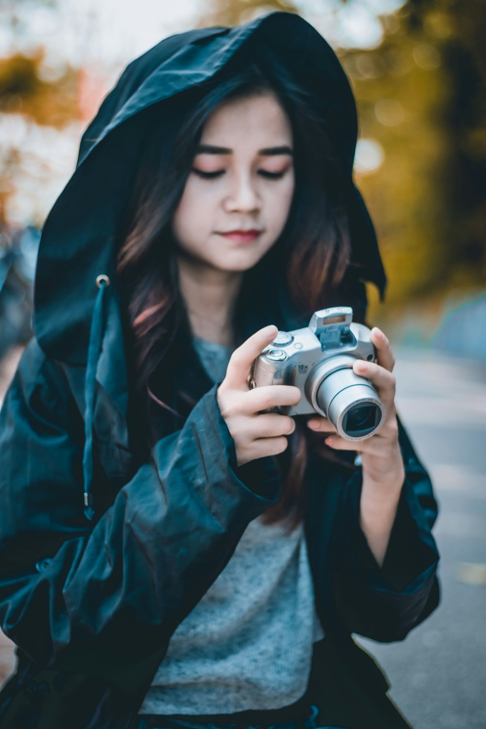 woman in blue jacket holding black and silver camera