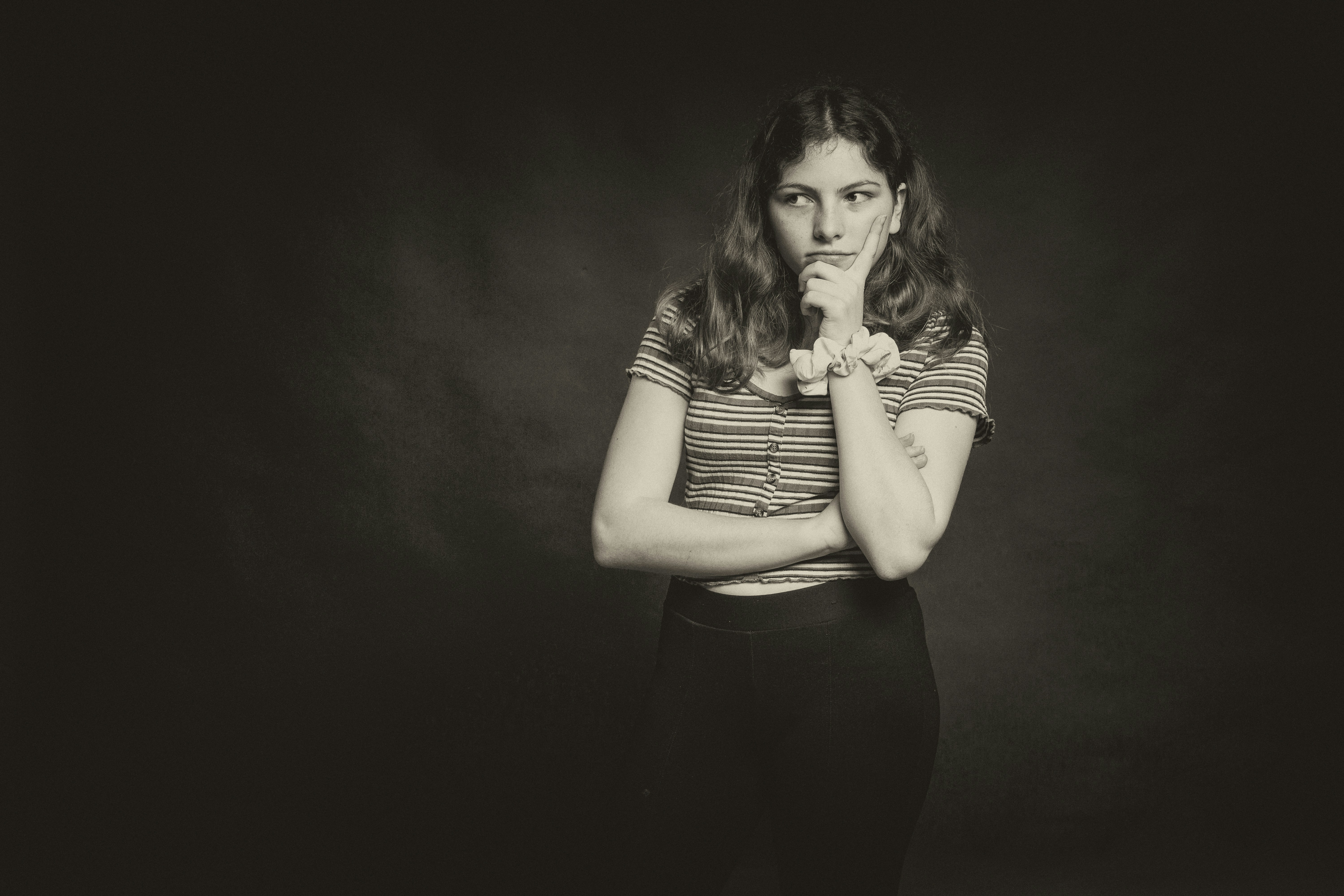 woman in black tank top and black pants deeply thoughtful teams background