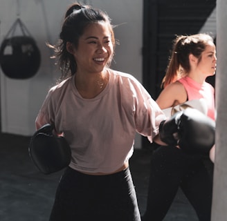 woman in pink long sleeve shirt and black pants holding black kettle bell