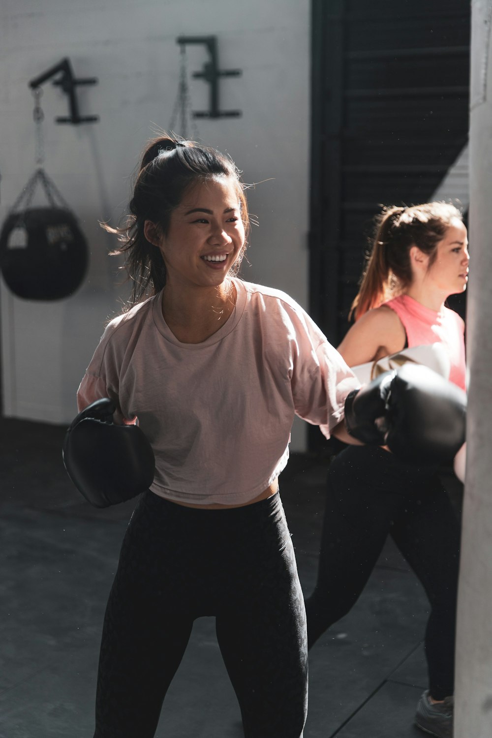 Frau in rosa Langarmhemd und schwarzer Hose mit schwarzer Kettlebell