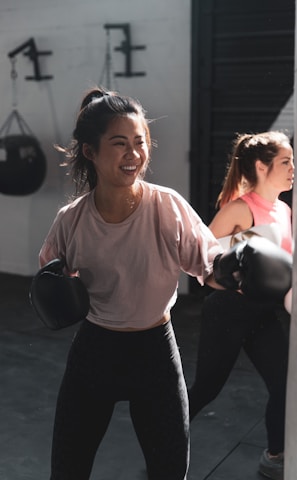 woman in pink long sleeve shirt and black pants holding black kettle bell