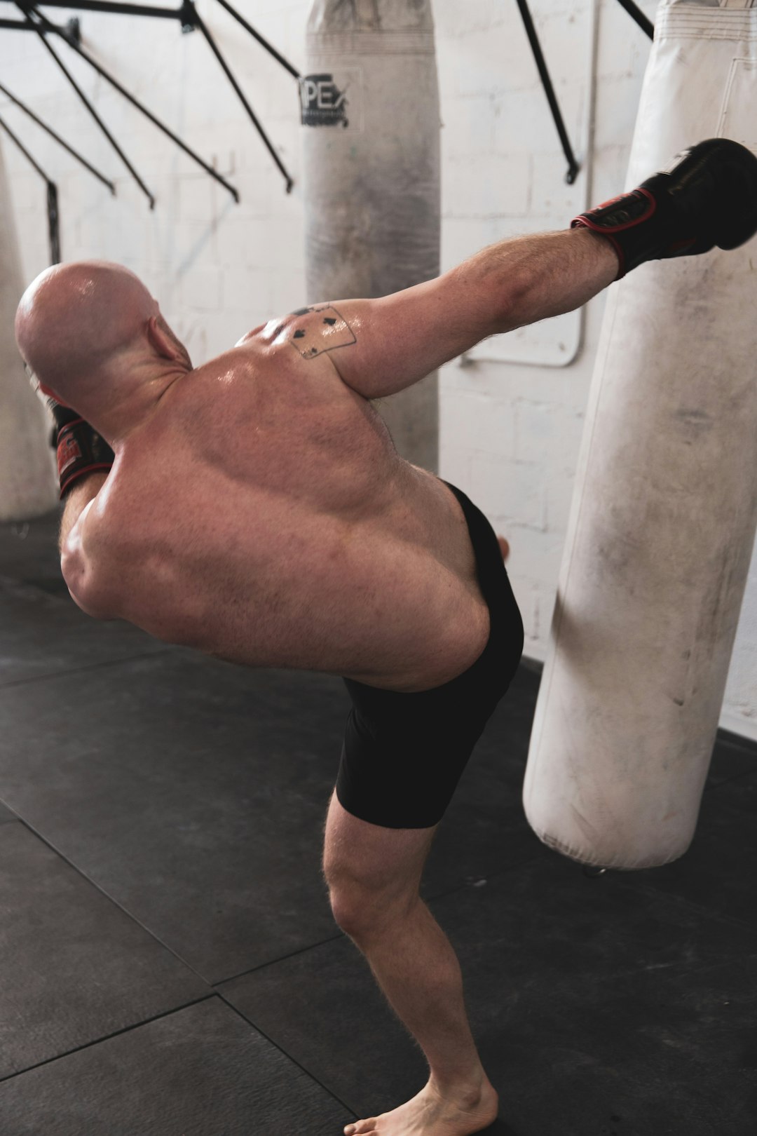 man in black shorts leaning on white wall