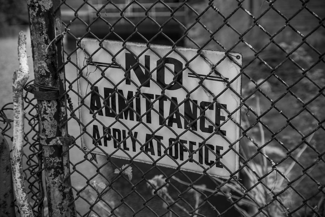 grayscale photo of metal fence with no smoking sign,