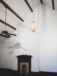 An electrician installing a ceiling fan in a modern living room.