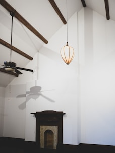 An electrician installing a ceiling fan in a modern living room.