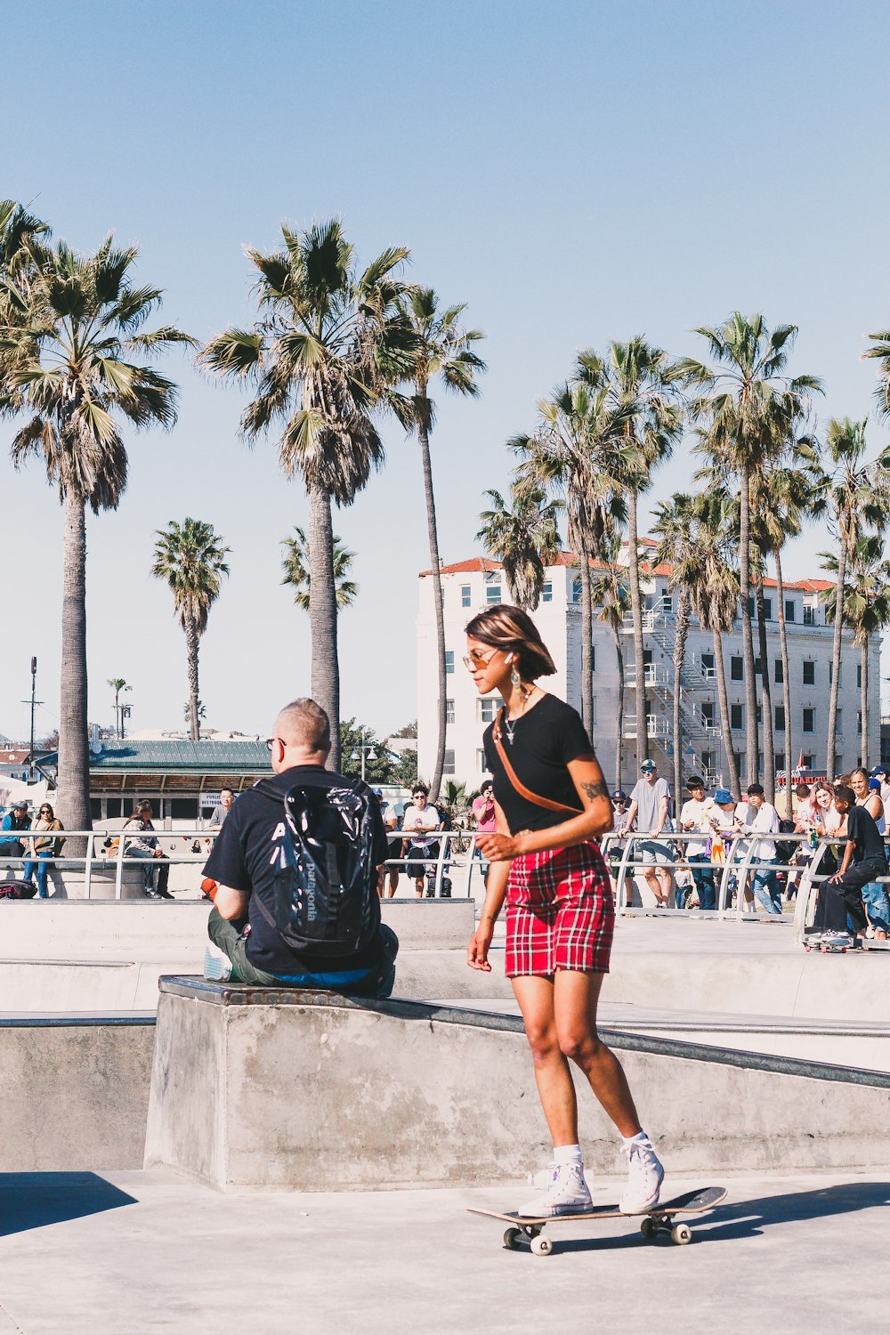 woman in black tank top and red skirt standing on gray concrete pavement during daytime