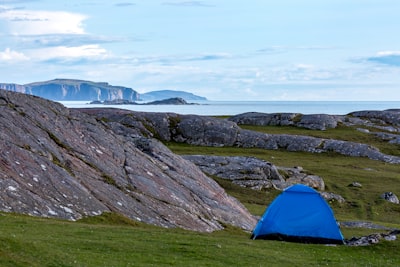 blue dome tent on green grass field near mountain under white clouds during daytime leisure activity google meet background