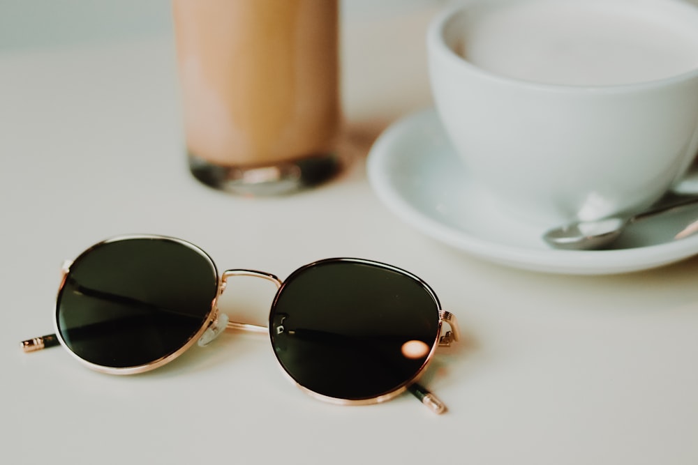 silver framed aviator style sunglasses on white ceramic saucer