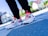 A pair of colorful athletic shoes on a person's feet, with a focus on detailed design and vibrant colors. The background is blurred with an outdoor setting giving a sense of movement or urban style.
