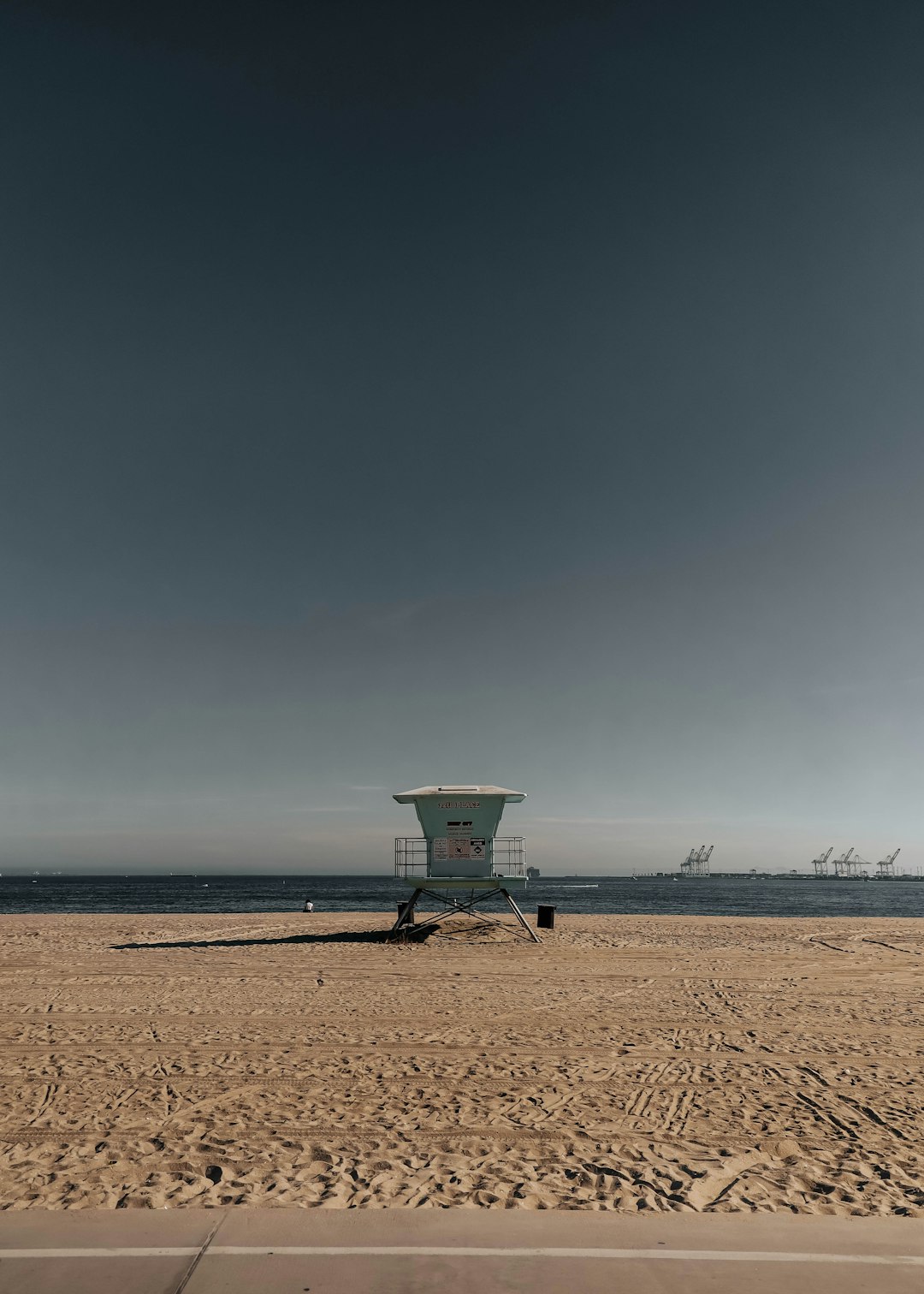 blue and white lifeguard tower on brown sand near sea during daytime