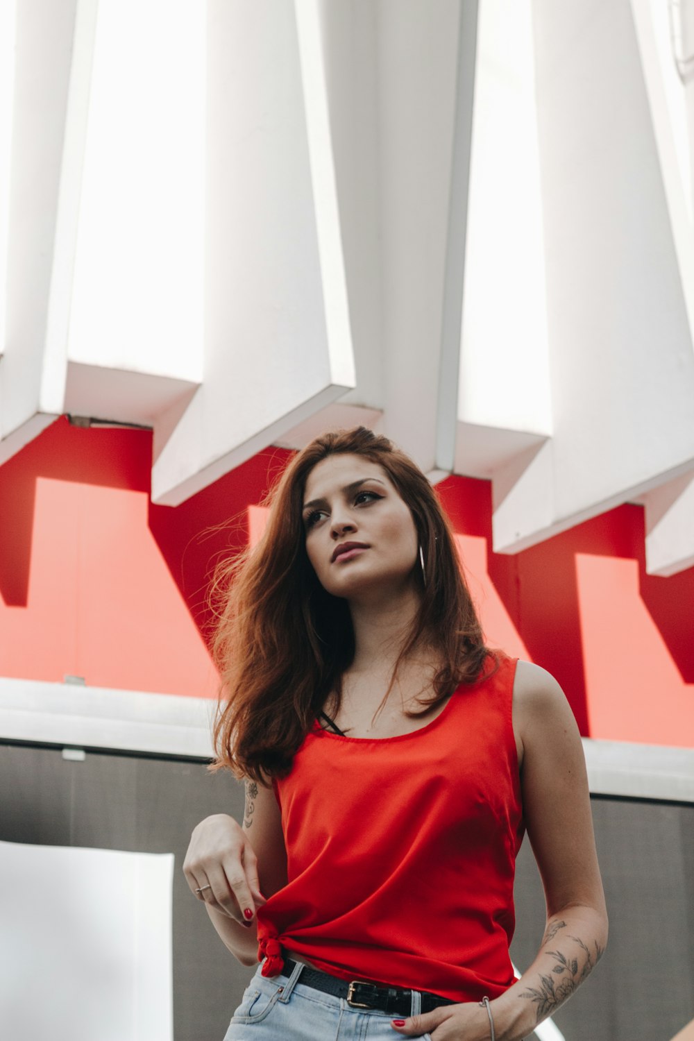 woman in red tank top standing near white wall