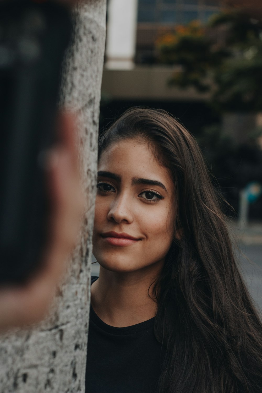 woman in black shirt leaning on white metal fence during daytime