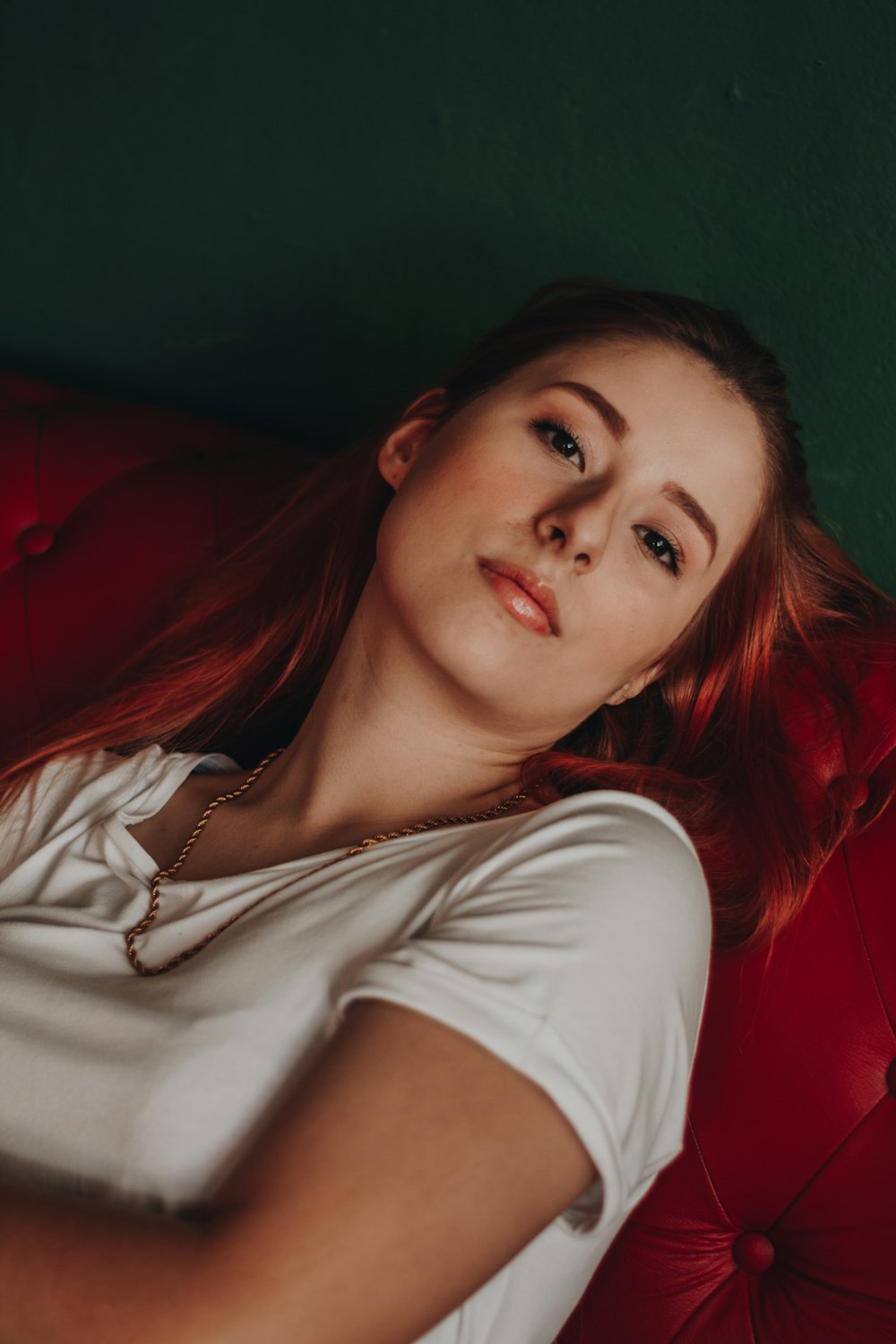 woman in white shirt lying on red sofa