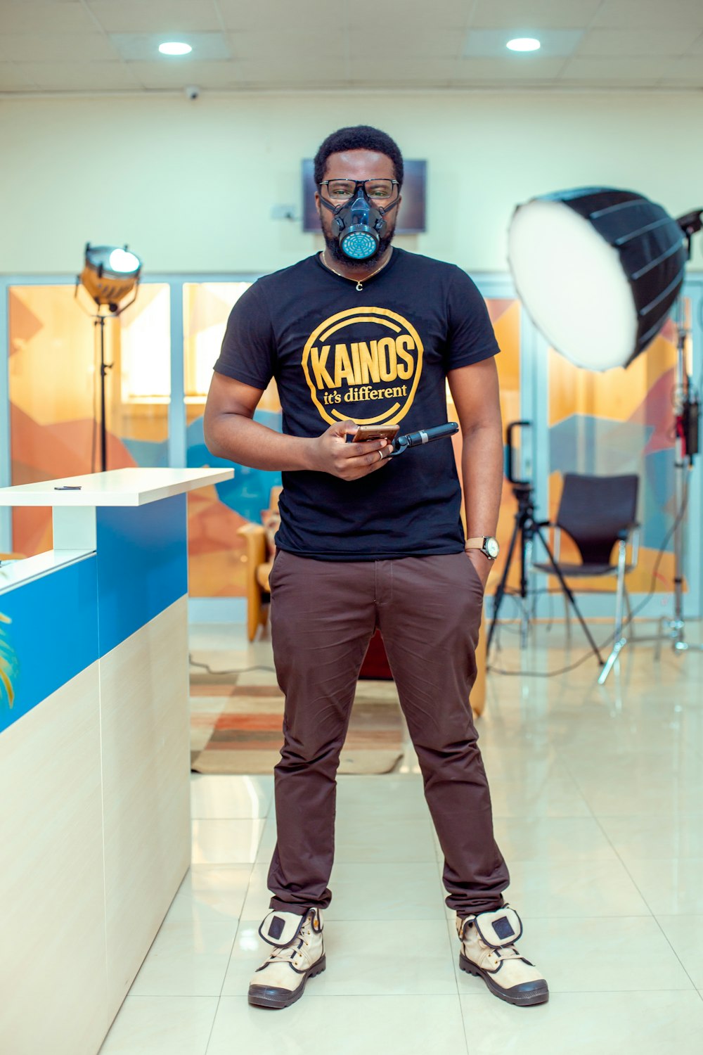 man in black and yellow crew neck t-shirt and brown pants standing on brown floor