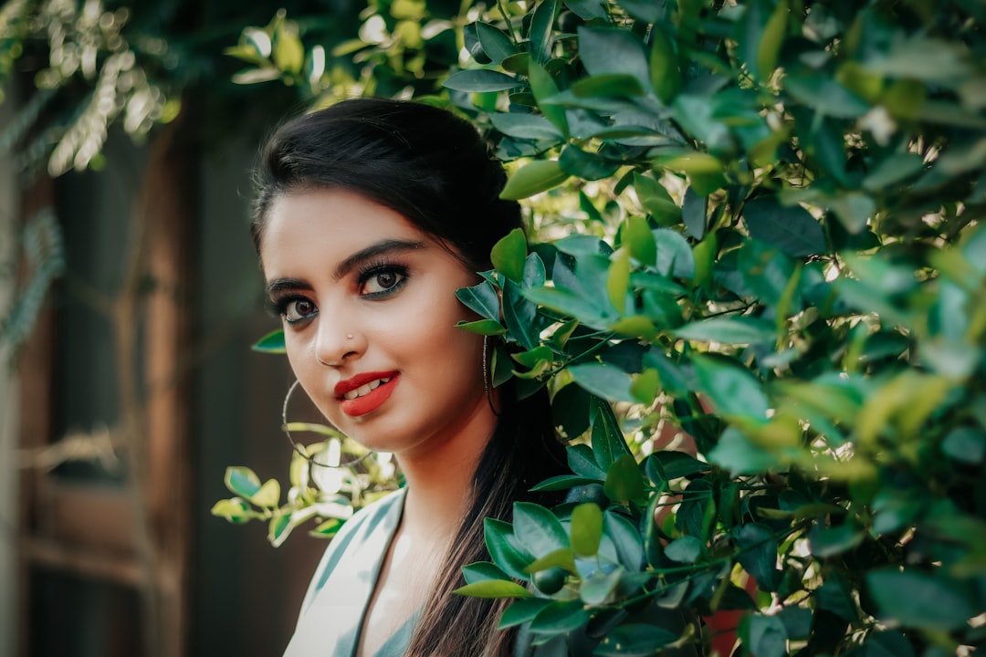 woman in white collared shirt standing beside green leaves