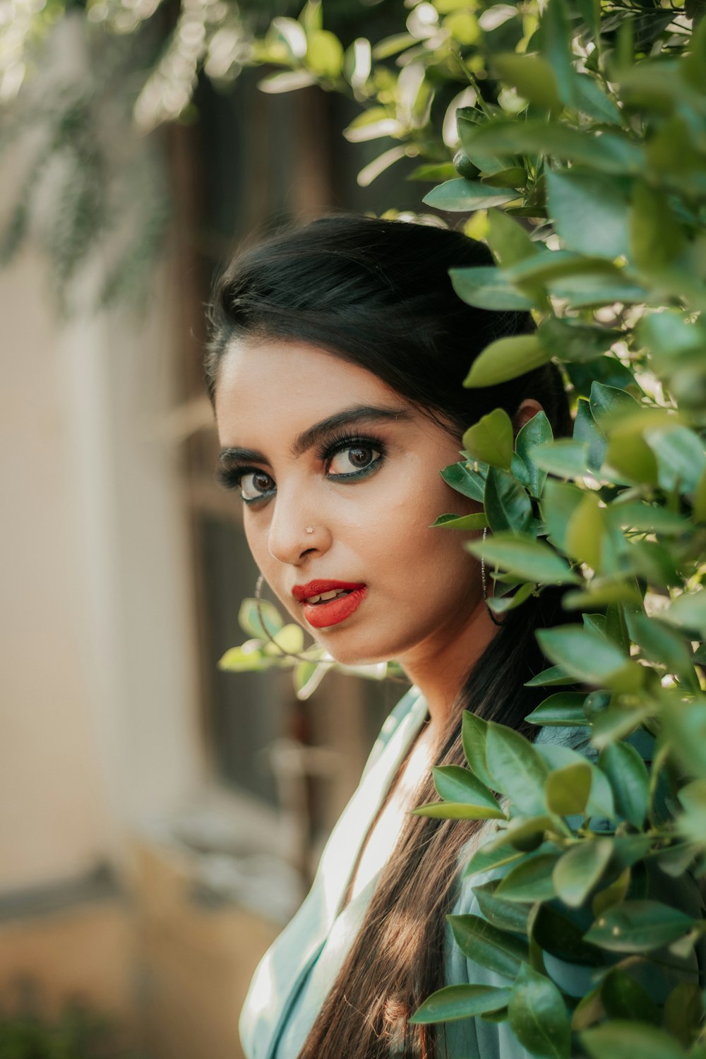 woman in white collared shirt standing beside green leaves