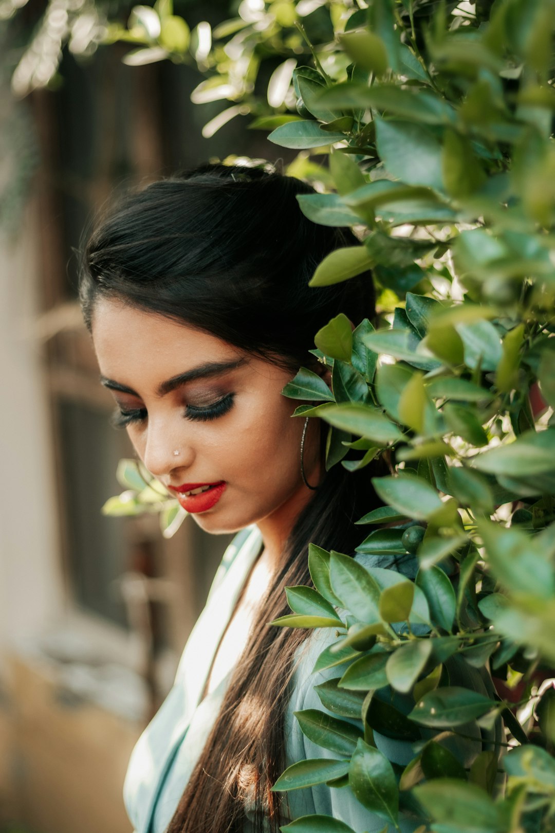 woman in white collared shirt standing beside green leaves