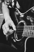 Close-up of hands playing basic guitar chords on an acoustic guitar.