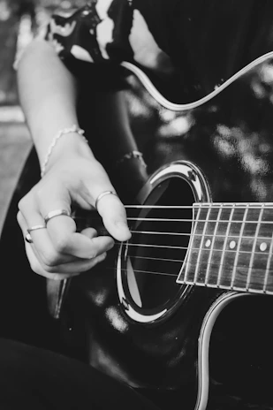 Close-up shot of hands gently playing an acoustic guitar, highlighting texture and detail.
