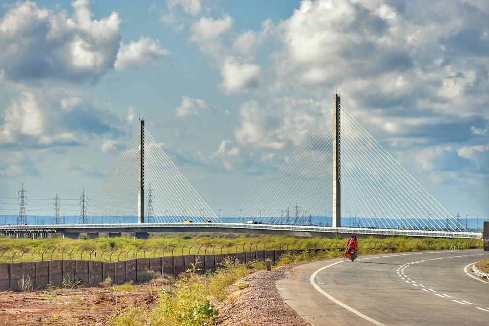 person in red shirt and blue denim jeans walking on gray concrete road during daytime