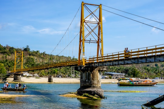 brown bridge over river under blue sky during daytime in Ceningan island Indonesia