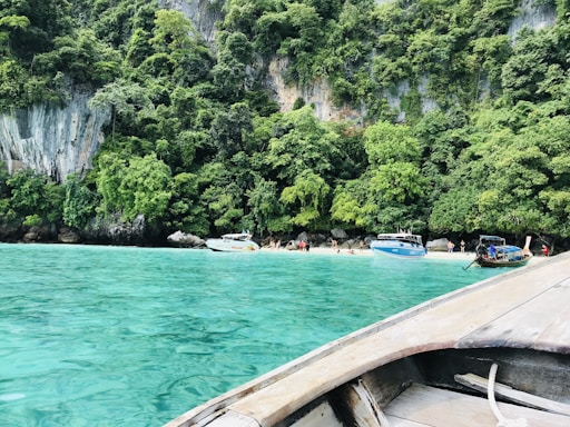 A serene beach with turquoise waters and a fastboat anchored near the shore.