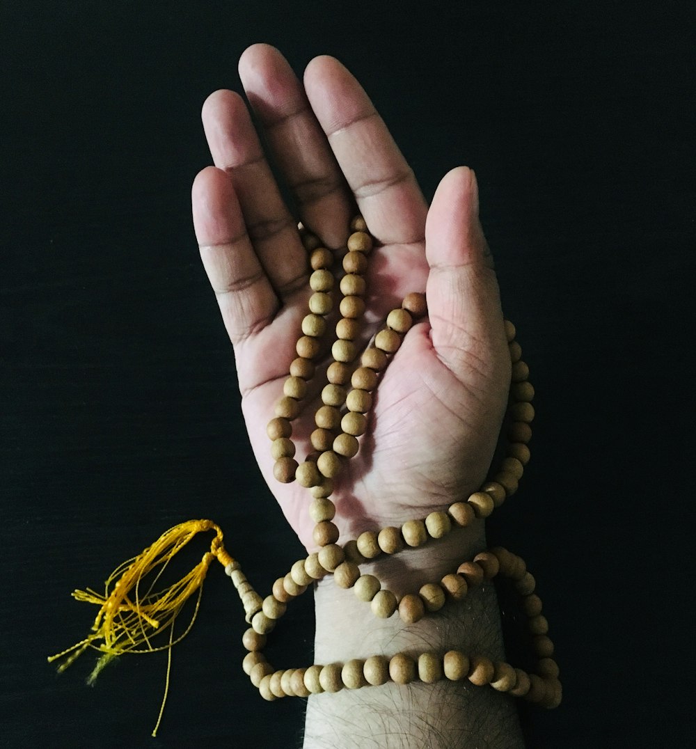 person holding brown beaded necklace