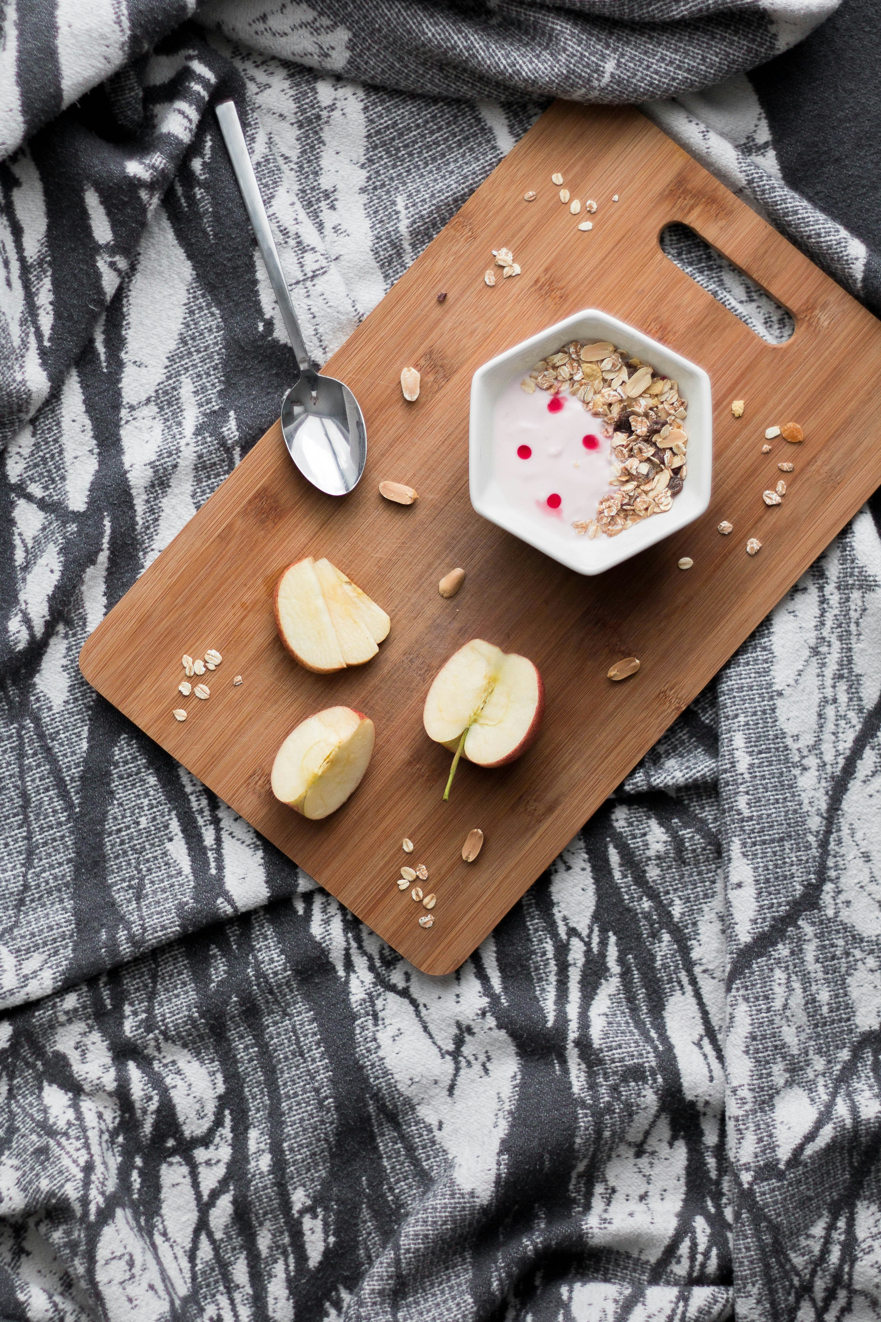 stainless steel spoon beside white ceramic bowl on brown wooden chopping board