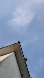 Close-up of a lightning rod on a building rooftop under blue sky.