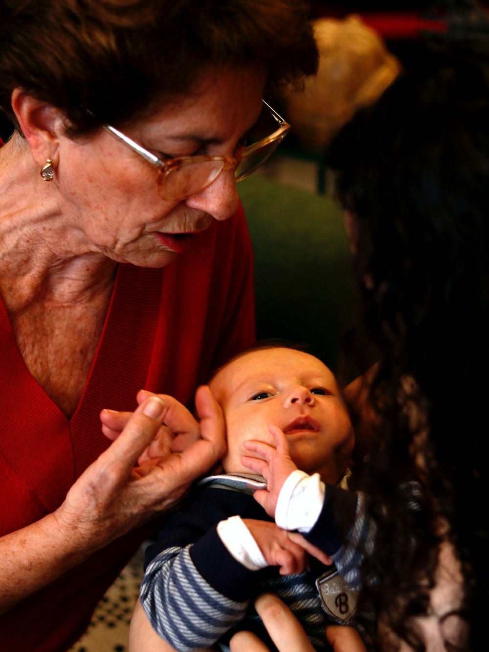 man in red shirt carrying baby in white and black striped shirt