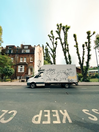 A sleek white delivery van parked outside a modern warehouse, ready for dispatch.