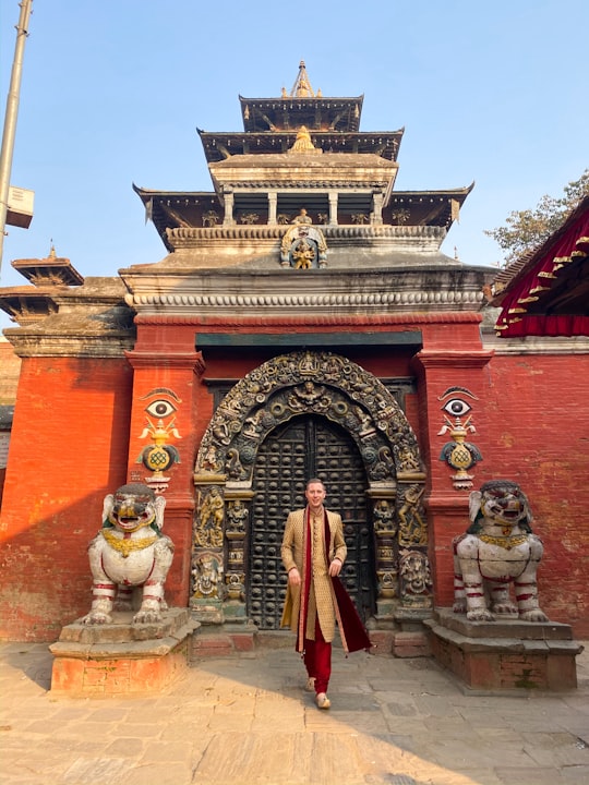 woman in red dress standing in front of brown concrete building in Kathmandu Durbar Square Nepal