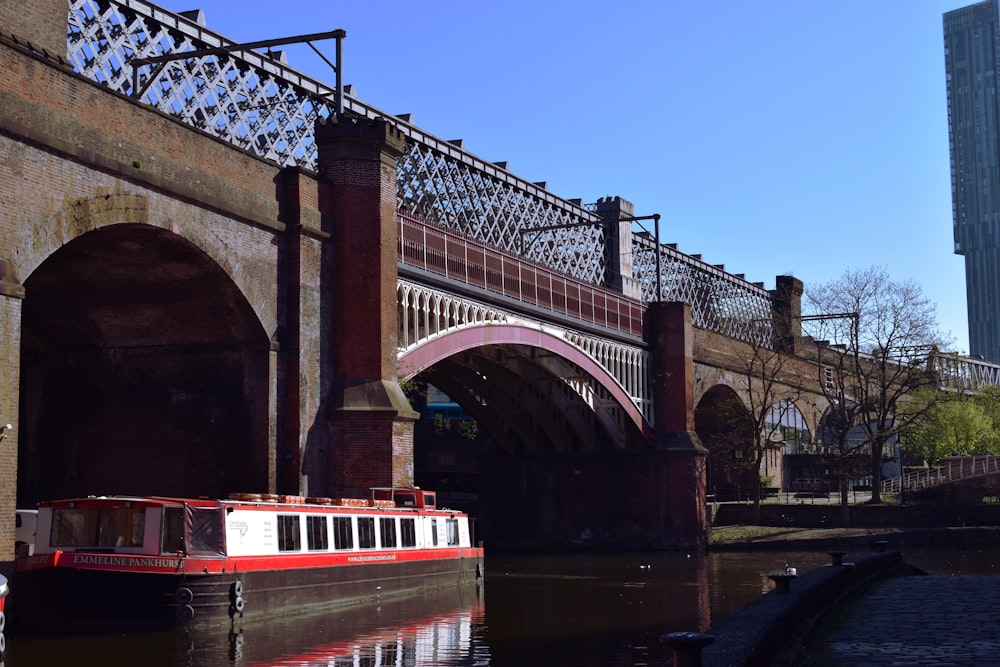 barca bianca e rossa sotto il ponte durante il giorno